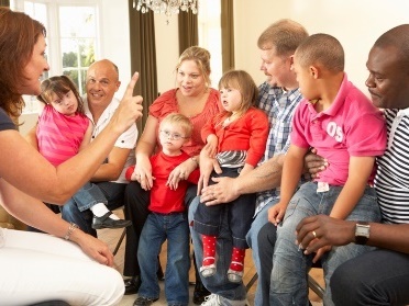 A large group of children with disability and their parents having a meeting.