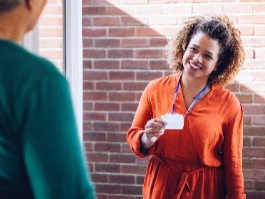 A person with a lanyard checking in on another person.