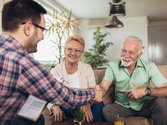 A man meeting with two elderly people and shaking their hands.
