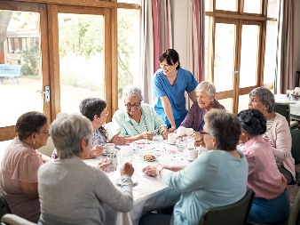 A group of elderly people sitting around a table in an aged care home.