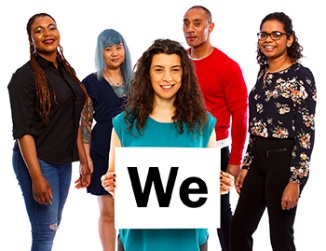 A group of people. There is a woman at the front of the group, she is holding a card that says "we". 