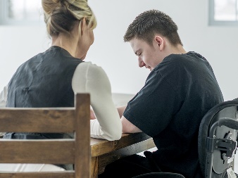 A woman and a young man sitting at a table and talking.