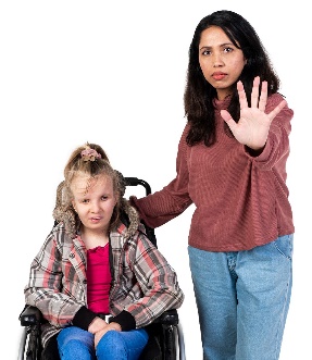 A woman holding up her hand, indicating 'stop'. Her other hand is supporting a young girl in a wheelchair.