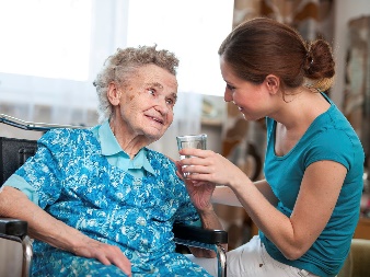 A woman giving a glass of water to an older woman. 