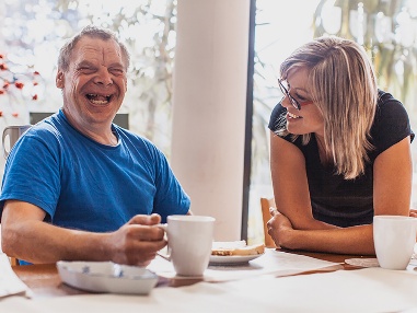 2 people sitting at a table together. Both are smiling.