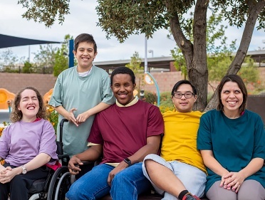 A group of people with disability from different backgrounds sitting and smiling together.