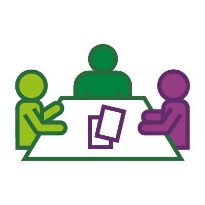 3 people talking around a table. There are papers on the table. 