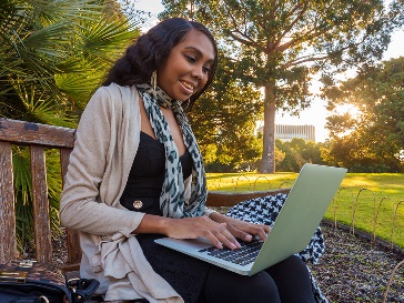 An NDIS worker using a laptop outside.