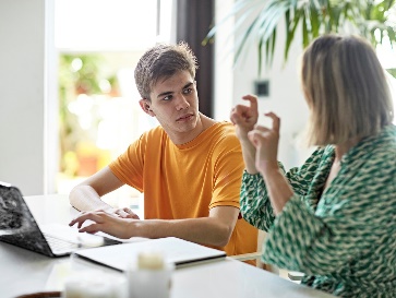 A participant and a worker having a conversation and using a laptop together.