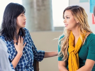 A group of people having a conversation. A worker is supporting a participant to take part.