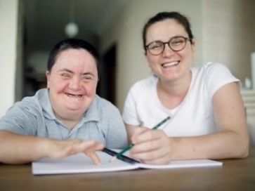An NDIS worker supporting a participant to read a document.