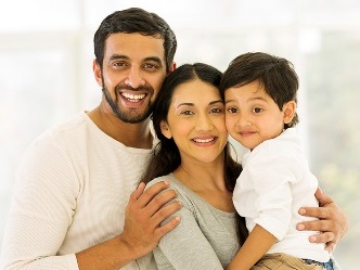 2 parents with their child smiling together.