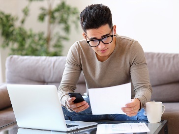 A person from NDIS Care using a laptop and looking at a document.