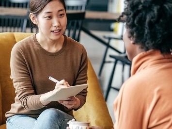 A participant and a worker having a conversation. The participant is writing on a document.