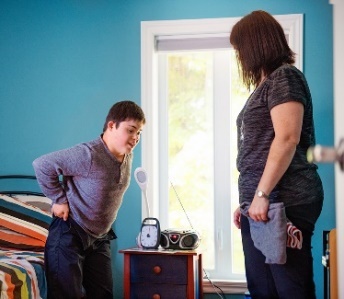An NDIS worker supporting a participant who is getting dressed.