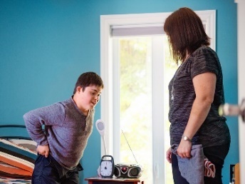 An NDIS worker supporting a participant who is getting dressed.