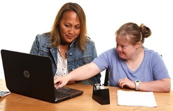 A participant and a worker using a laptop together.