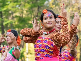 A group of people wearing brightly coloured clothing and performing a cultural dance.