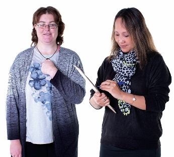 A participant pointing at themselves next to a worker writing on a document.