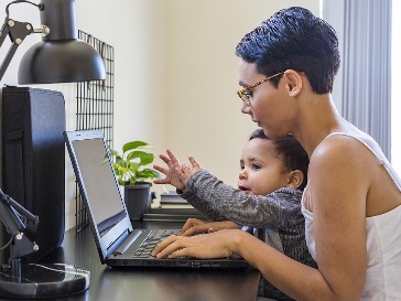 A participant using their laptop with a baby on their lap.