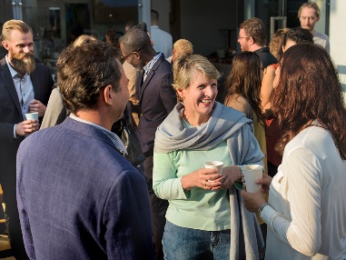 A group of people having a conversation at an event with a lot of people in the background.