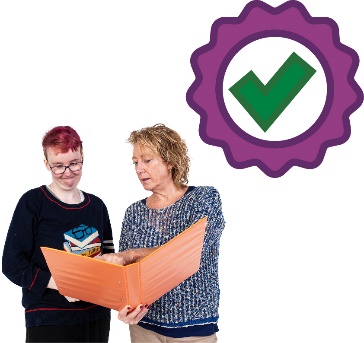 A worker supporting a participant to read a document. Above them is an icon showing good quality.