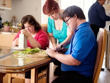 A person supporting people with disability to cook in their home.