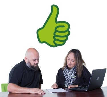 A thumbs up over 2 people working together at a desk.