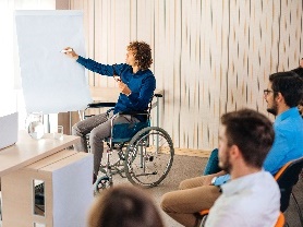 A person in a wheelchair giving a speech to a group of people. 