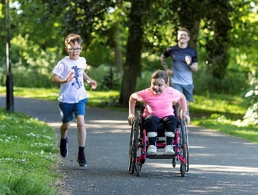 3 young people with disability racing in a park.