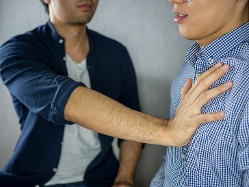 Someone with their hand on someone's chest, pushing them.