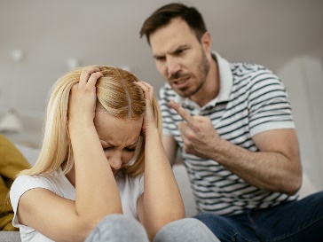 A person looking angry with a finger raised at someone, who has their hands over their face.