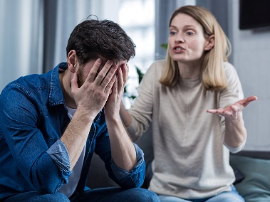 A person yelling at someone, who has their hands over their face.