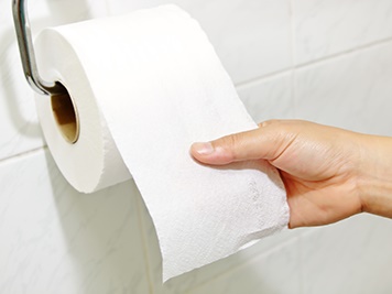 Someone pulling toilet paper from a toilet paper roll.