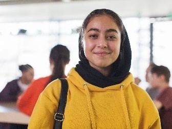 A smiling young person wearing a hijab.